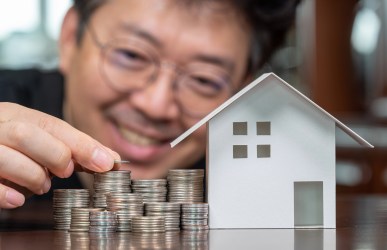 Man with coins and a small house