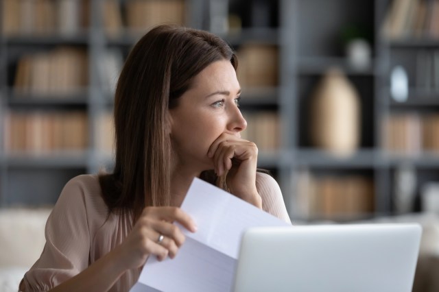 Woman holding a piece of paper looking stressed
