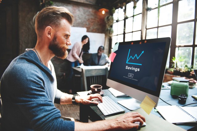 Man at computer with a screen reading "Savings" and showing a growing balance