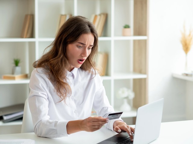 Woman reviewing a credit card bill on her laptop while researching debt validation and verification letters.